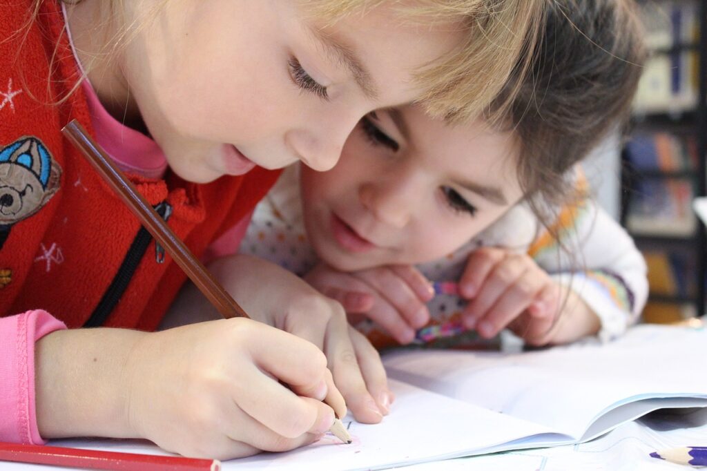 one child writing while second child looks on