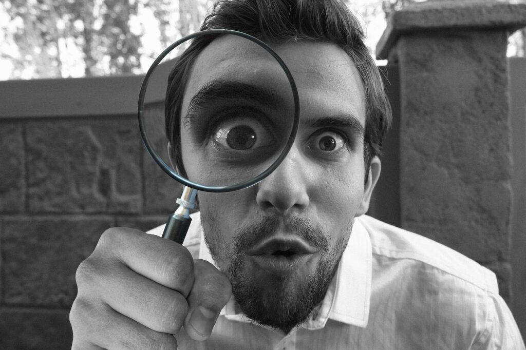 Man with magnifying glass over eye showing curiosity